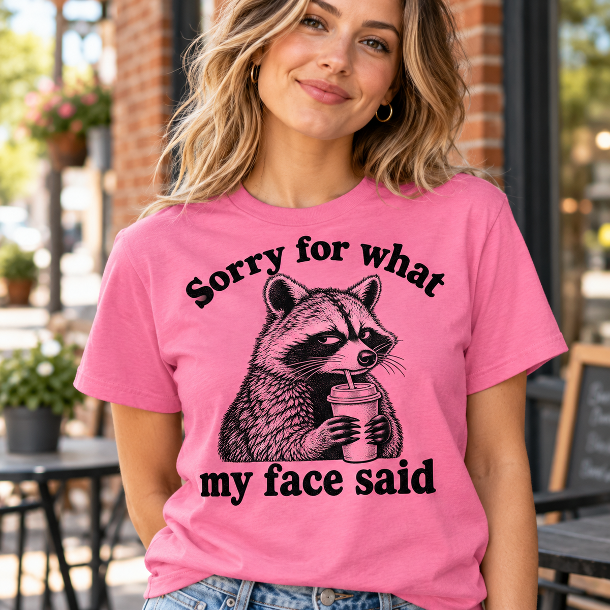 Woman wearing pink Sorry for What My Face Said raccoon graphic tee